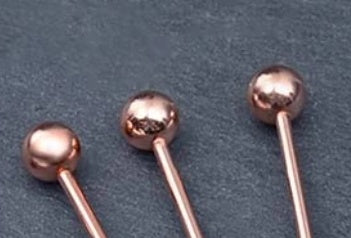 Shopi Vella fancy cocktail picks for parties with metallic rose gold ball tops on dark background