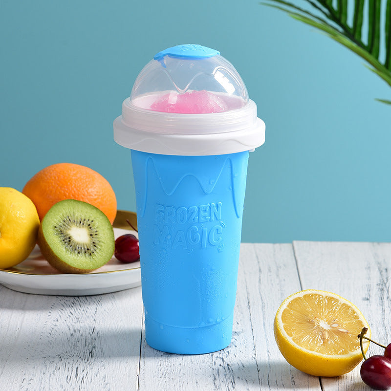 Shopi Vella blue instant frozen drink cup with clear dome lid on white wooden table with fresh fruit
