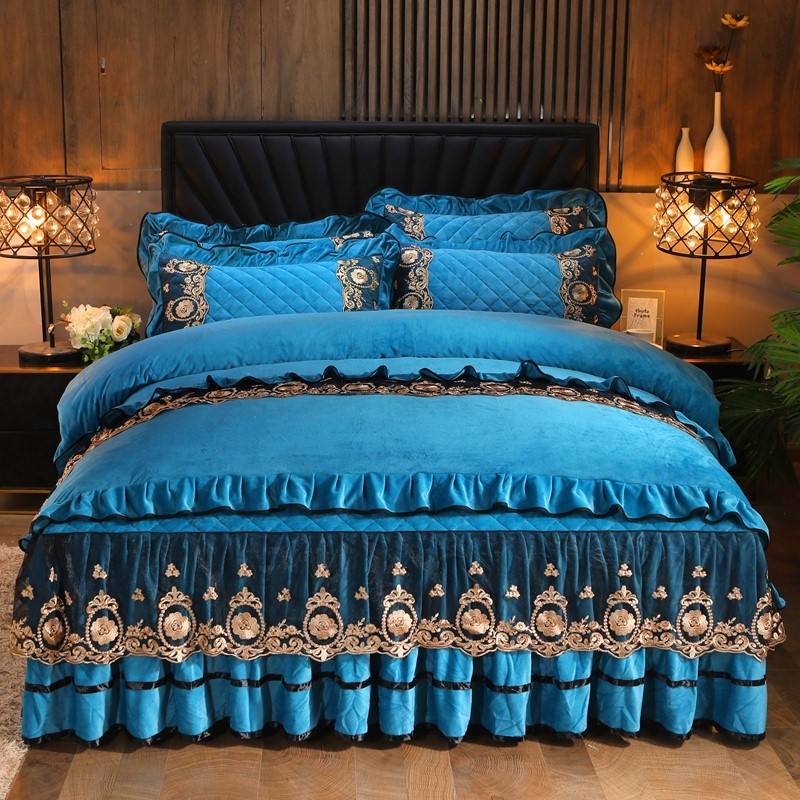Blue quilted comforter set with intricate gold embroidery on a black headboard bed in a cozy bedroom