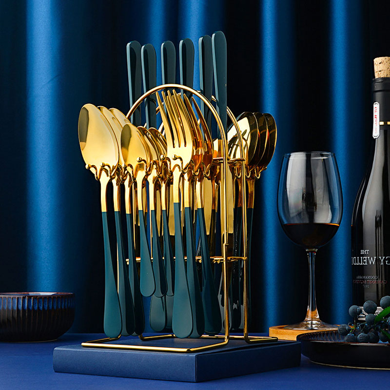 Stylish tableware for dinner parties with gold and black flatware set in a modern holder next to wine glass and bottle