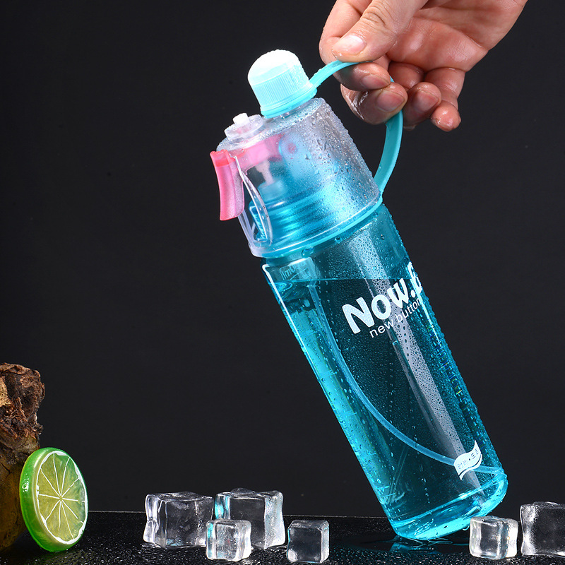 Blue leakproof water bottle with handle being held above ice cubes and lime slice on black background