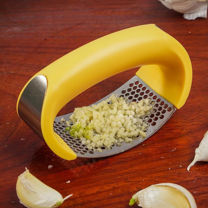 Shopi Vella stainless steel garlic press with yellow handle crushing fresh garlic cloves