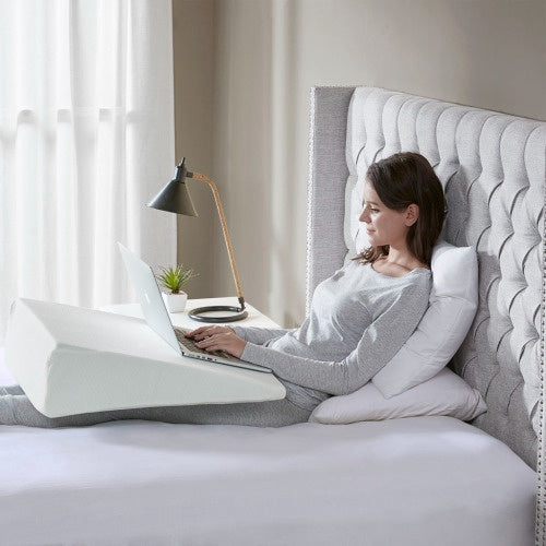 Woman using adjustable back support pillow on bed with laptop for comfortable working
