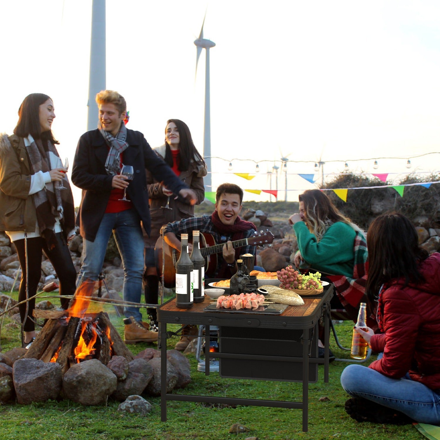 Group of friends enjoying outdoor gathering with adjustable height picnic grill table cooking skewers and drinks