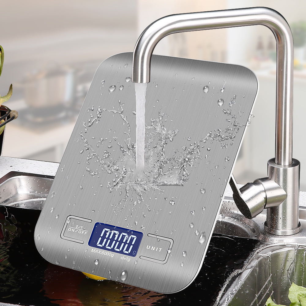 Shopi Vella 5kg kitchen measuring scale in stainless steel with digital display being washed under faucet