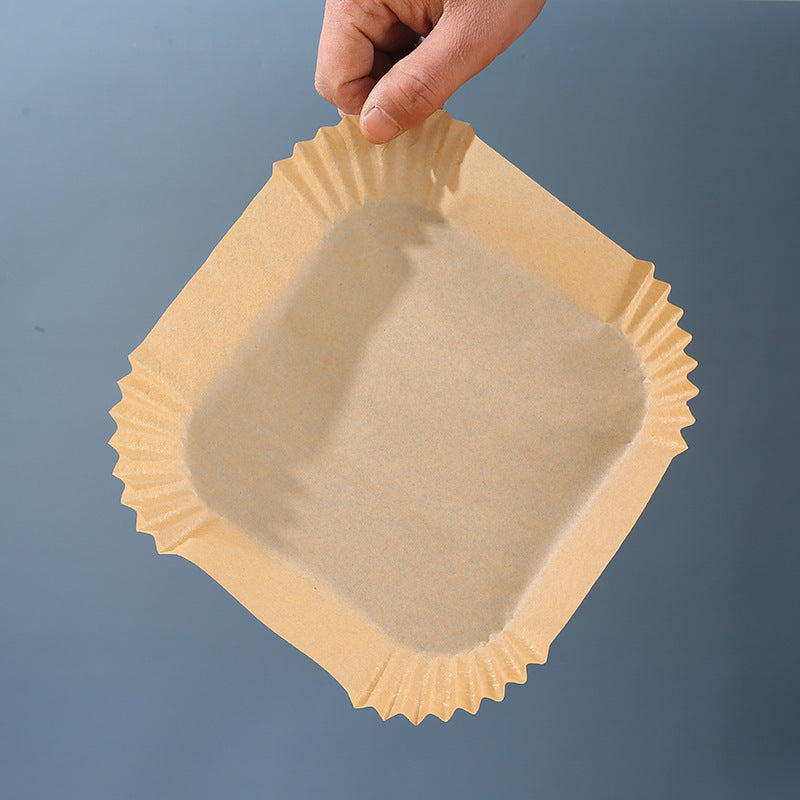 Shopi Vella air fryer disposable paper liners held above gray background for easy cleanup