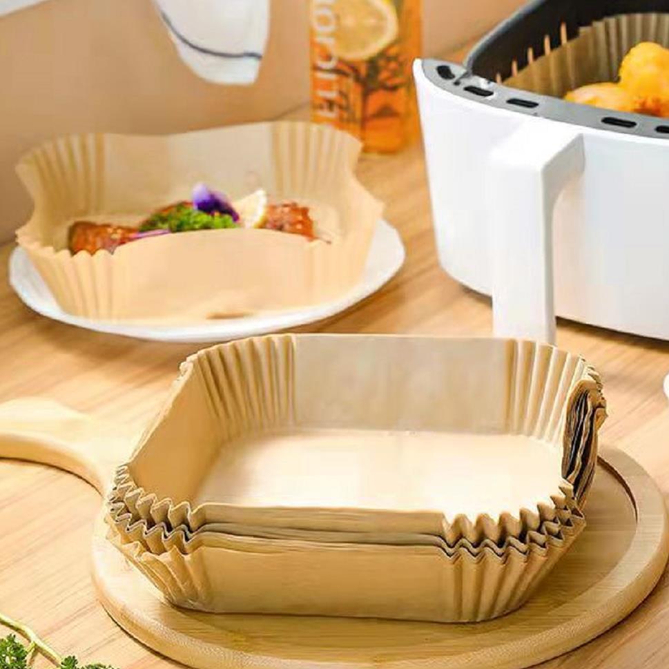 Shopi Vella air fryer disposable paper liners stacked on wooden board near cooked food and air fryer