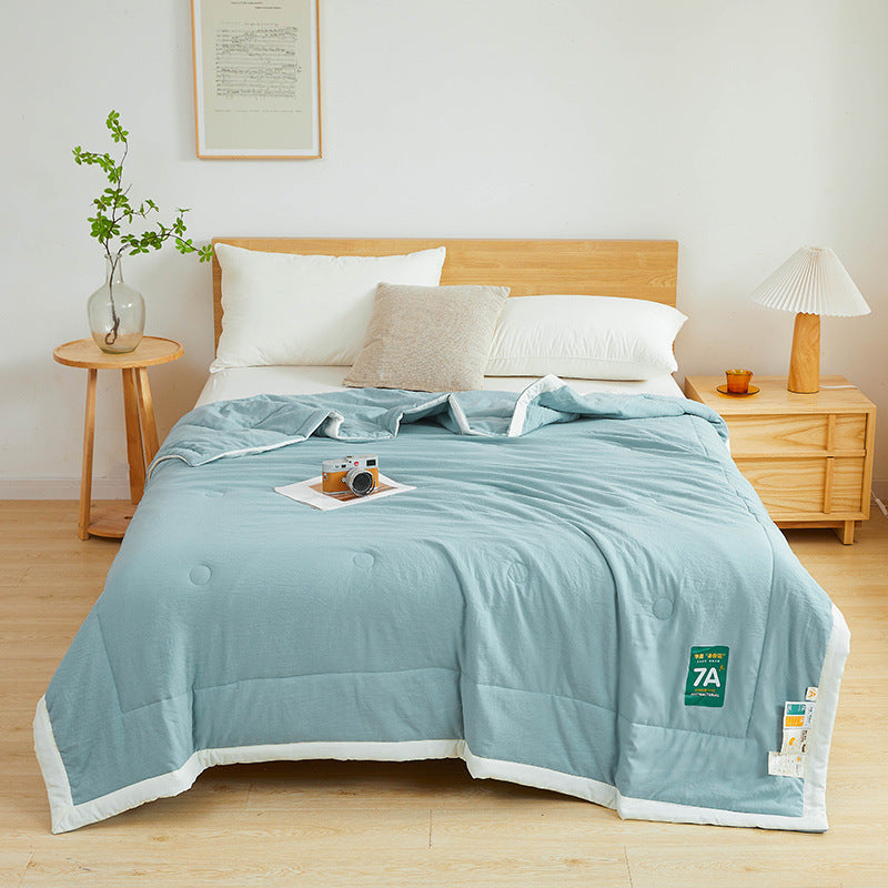 Shopi Vella antibacterial summer quilt in light blue on bed with white trim in minimalist bedroom