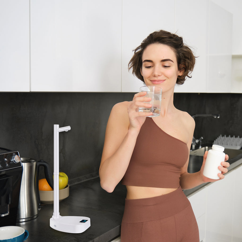 Woman drinking water in kitchen using Shopi Vella automatic water bottle dispenser on countertop