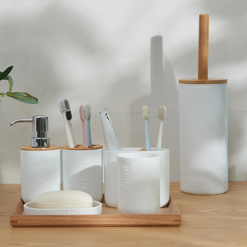White ceramic bamboo toothbrush holder set including soap dish soap dispenser and storage cups on wooden tray