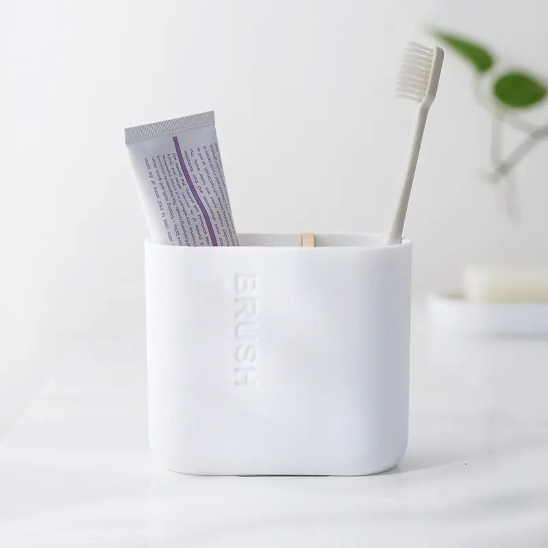 White bamboo toothbrush holder set with toothbrush and toothpaste on bathroom counter