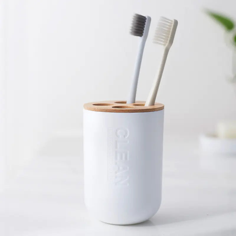 White bamboo toothbrush holder set with wooden top and two toothbrushes on a white countertop