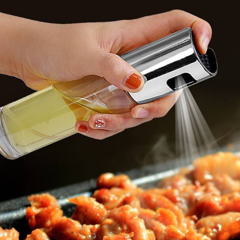 Hand spraying BBQ oil spray bottle over grilled meat for even cooking and flavor