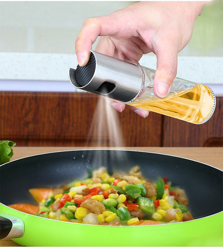 Shopi Vella BBQ oil spray bottle dispensing oil over a green frying pan with mixed vegetables