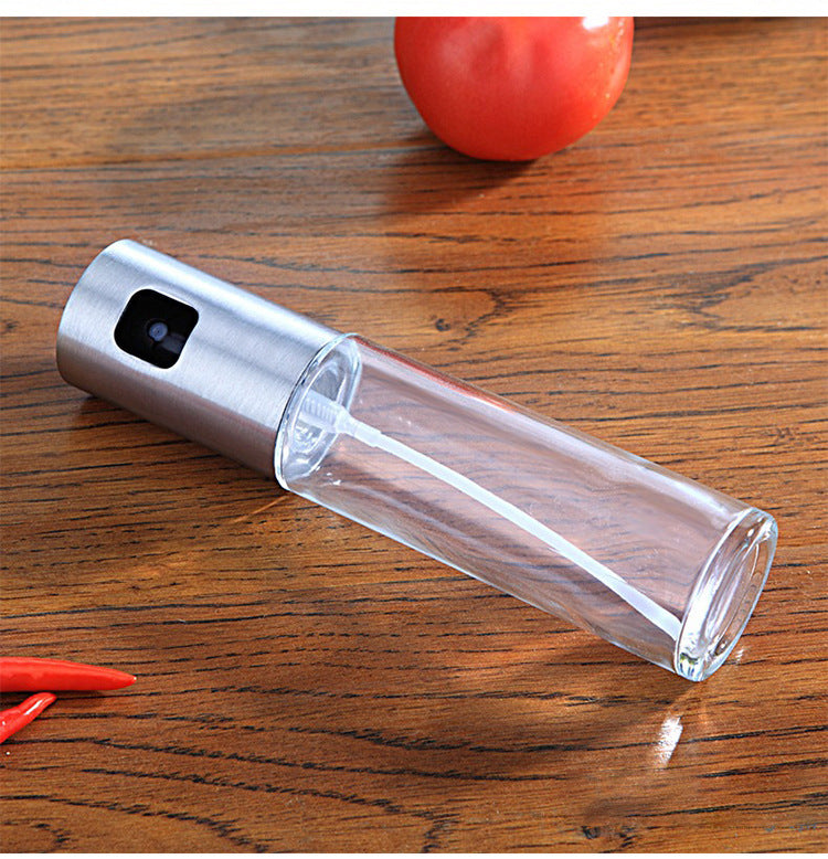Shopi Vella BBQ oil spray bottle with transparent body and stainless steel top on wooden surface