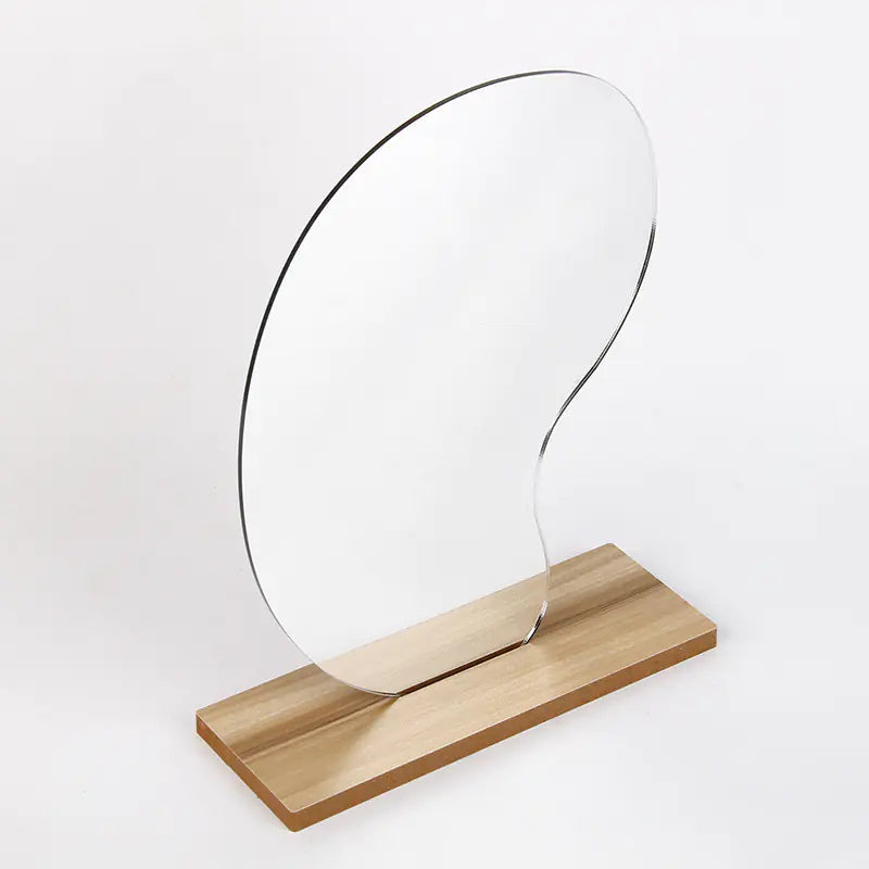 Modern clear glass dorm decor vanity mirror with an abstract shape on a wooden base