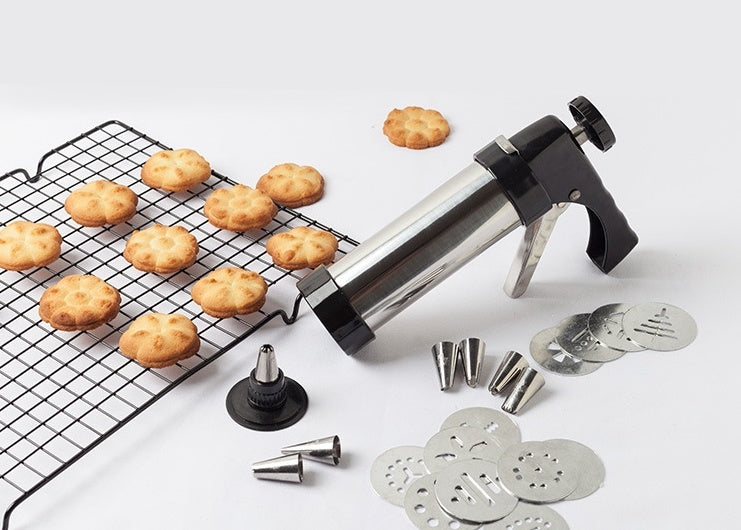 Shopi Vella biscuit press machine with multiple shaping discs and freshly baked biscuits on cooling rack