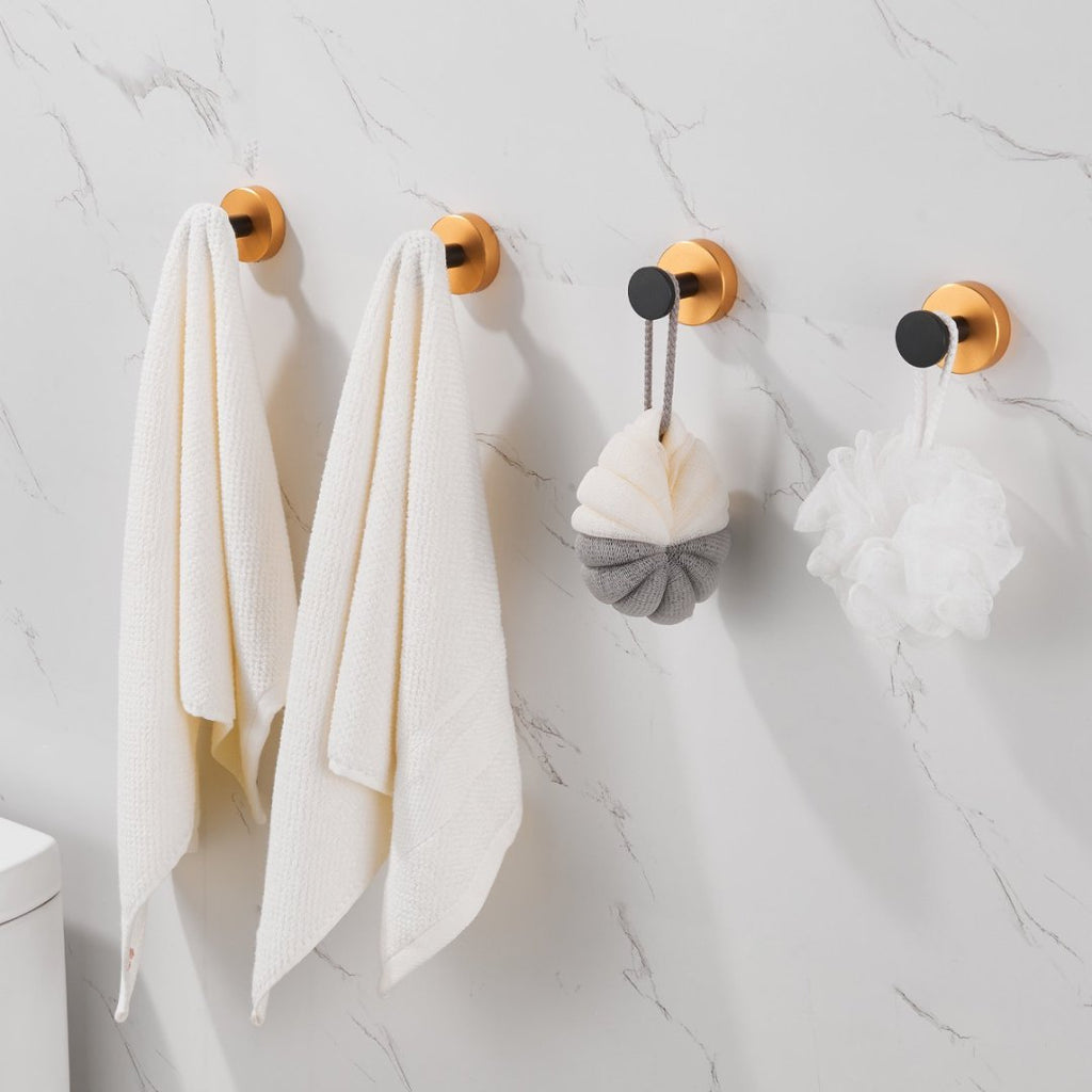 Shopi Vella black gold wall hooks set holding towels and bath sponges on marble bathroom wall