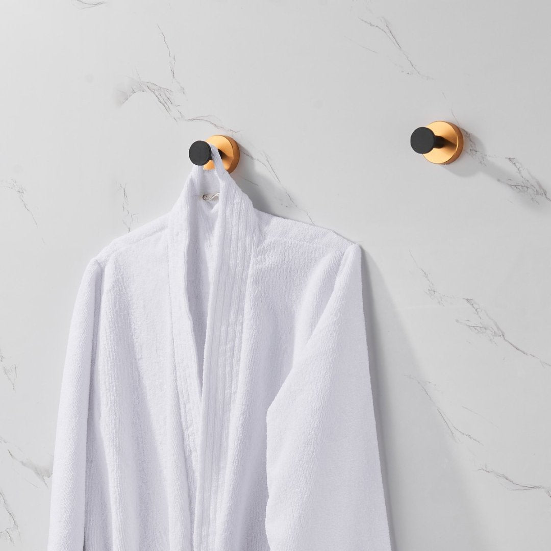 Shopi Vella black gold wall hooks set mounted on marble wall holding a white bathrobe
