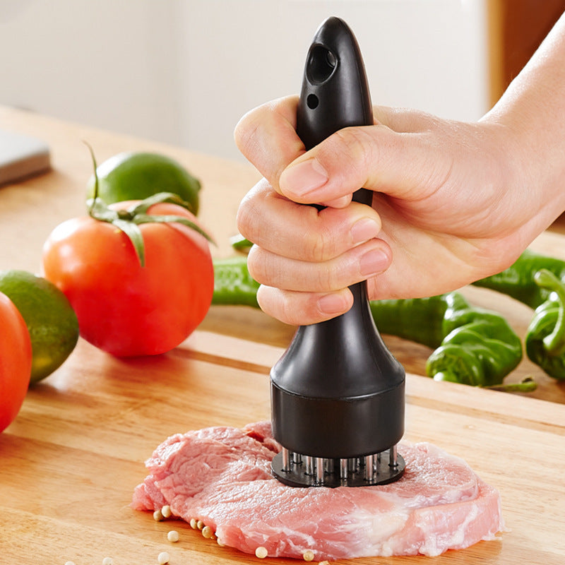 Shopi Vella stainless steel meat tenderizer with black handle pressing on raw meat on wooden cutting board