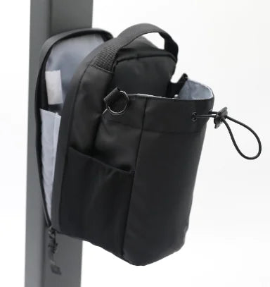 Black portable magnetic water bottle pouch attached to a backpack side pocket with adjustable drawstring