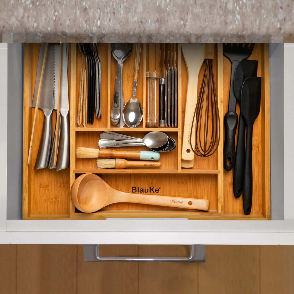 Expandable bamboo drawer organizer neatly storing kitchen utensils and cutlery in a kitchen drawer