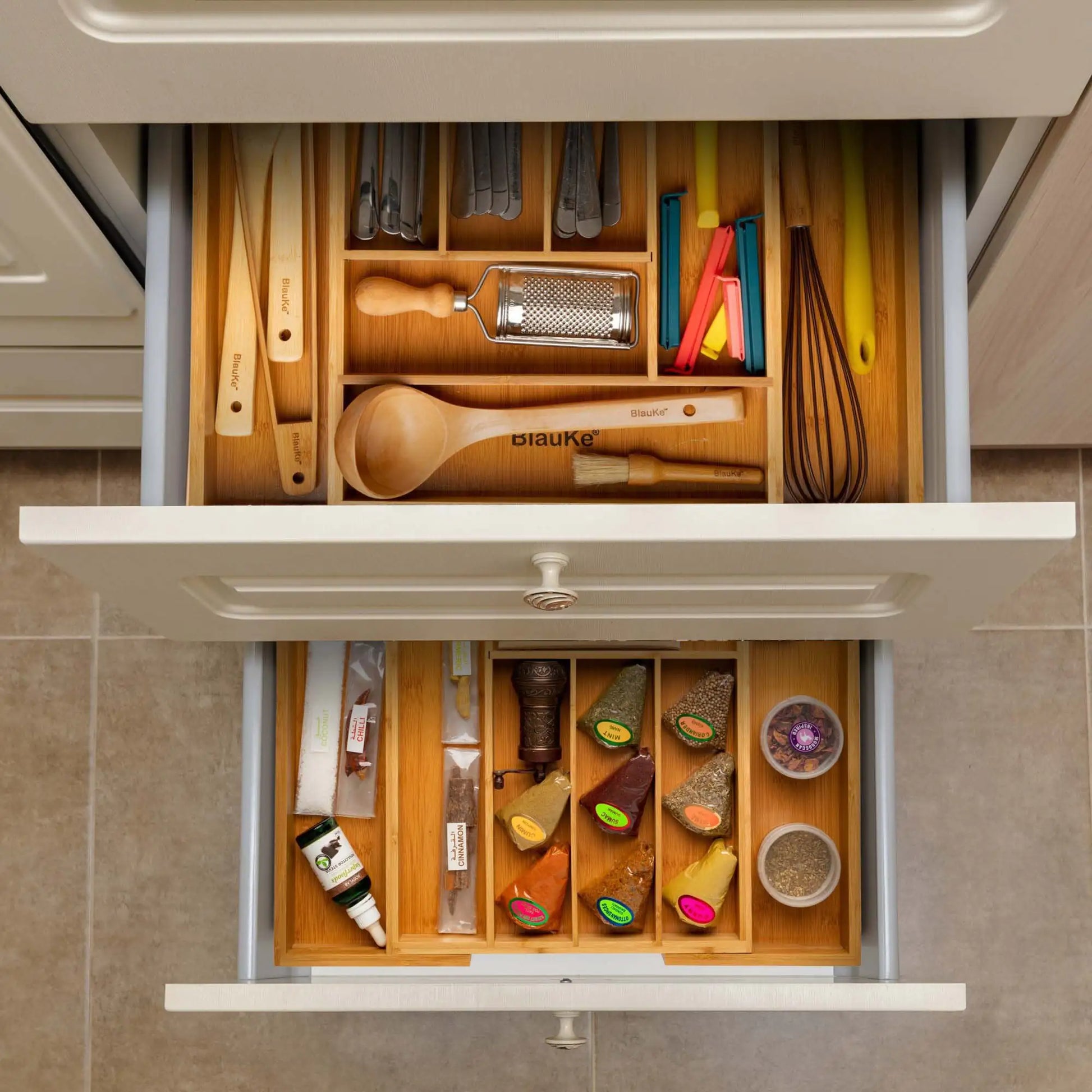 Expandable bamboo drawer organizer neatly holding kitchen utensils and spice containers in a kitchen drawer