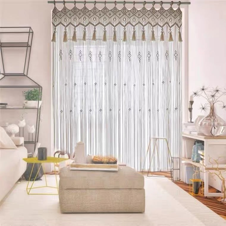 Bohemian hand woven curtain with tassels hanging in a bright living room with beige and white decor