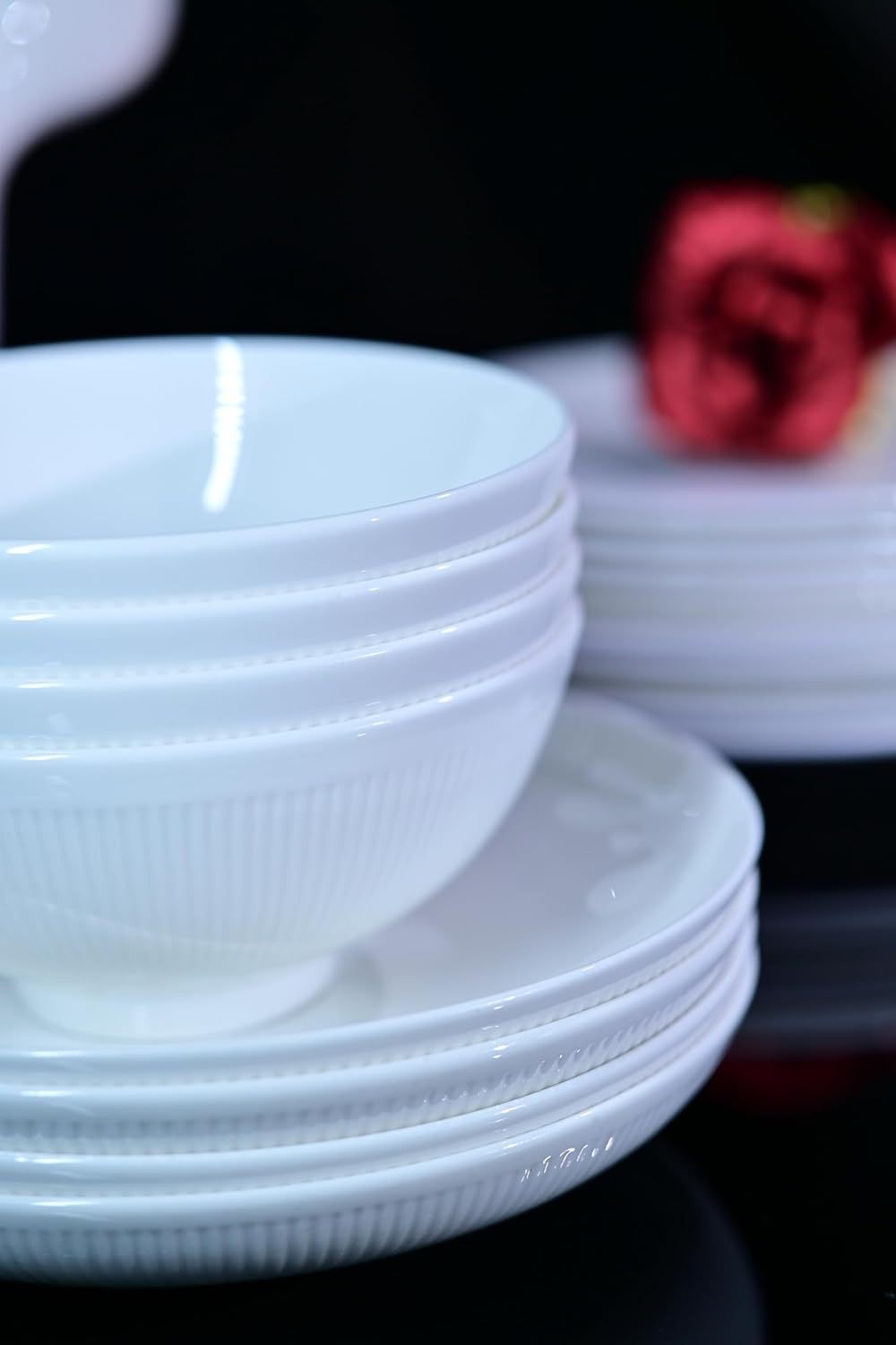 Shopi Vella bone china dinnerware set with white bowls and plates stacked neatly on black surface