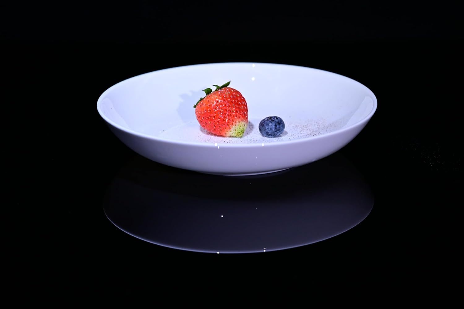 White bowl from Shopi Vella bone china dinnerware set with strawberry and blueberry on black background