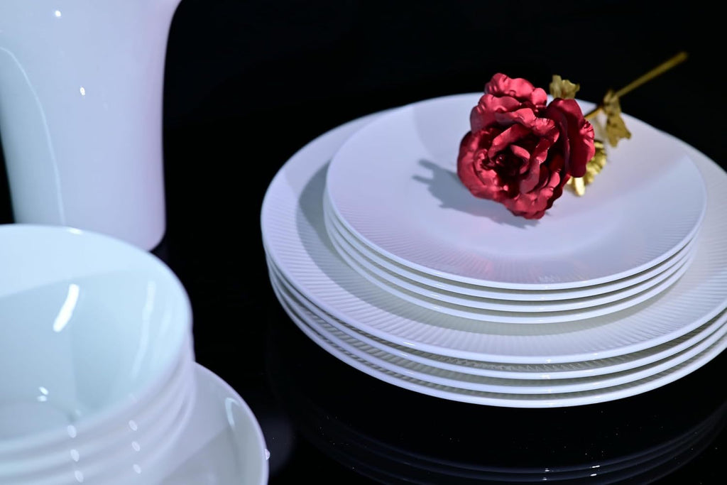 White bone china dinnerware set from Shopi Vella with stacked plates and a red decorative flower