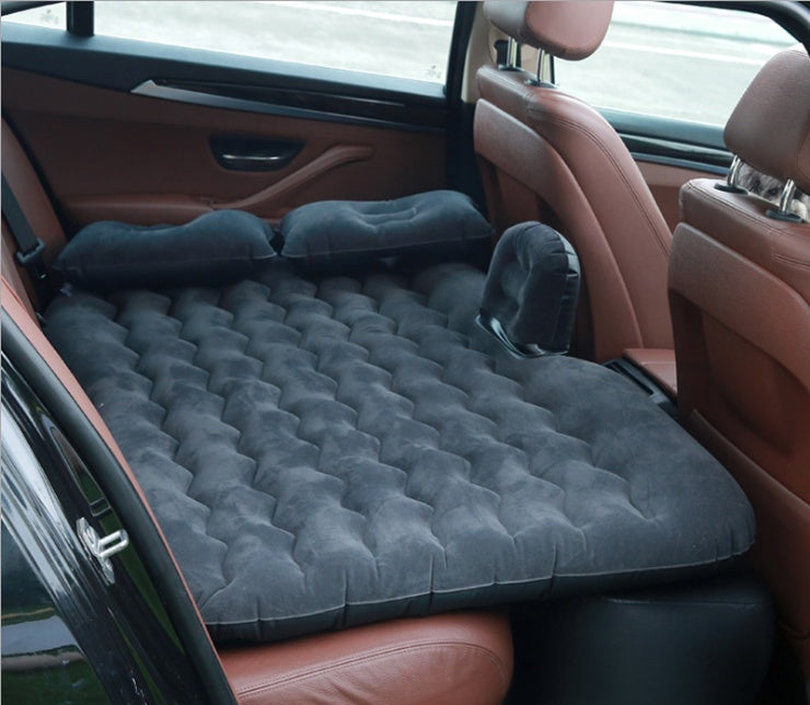 Black car inflatable bed fully set up in the backseat of a car with two pillows