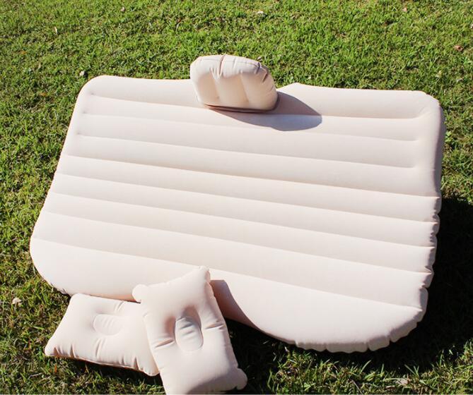 Beige car inflatable bed with pillows set up on green grass for outdoor use