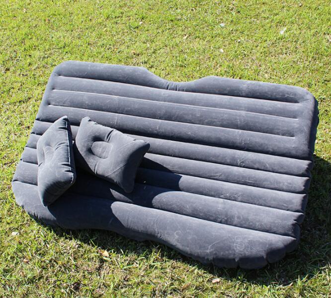 Gray car inflatable bed with two matching inflatable pillows placed on grass outdoors