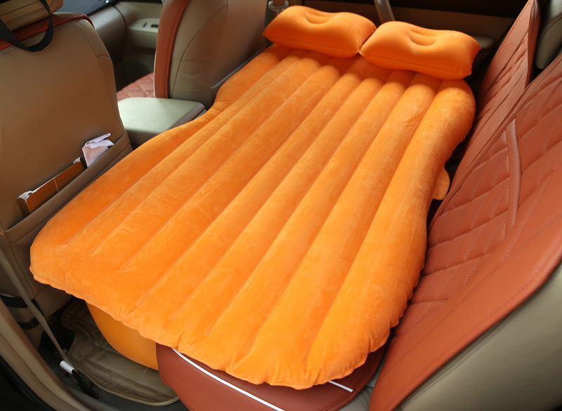 Orange car inflatable bed with two pillows set up on back seat for comfortable travel rest