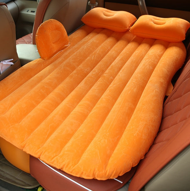 Orange car inflatable bed with two pillows set up in the backseat for comfortable travel rest