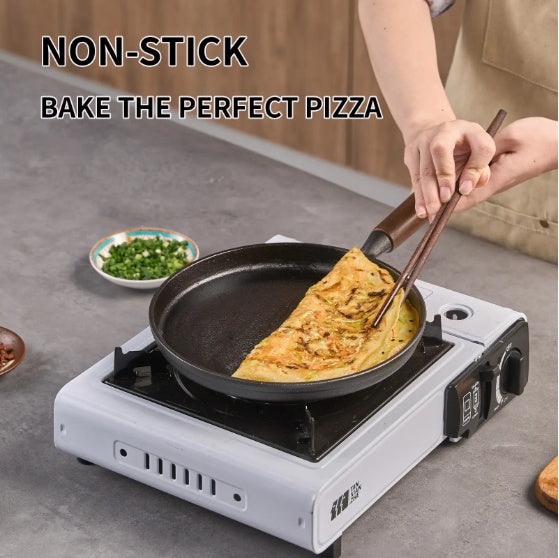 Shopi Vella cast iron pizza pan on portable stove with non-stick surface baking a golden pizza
