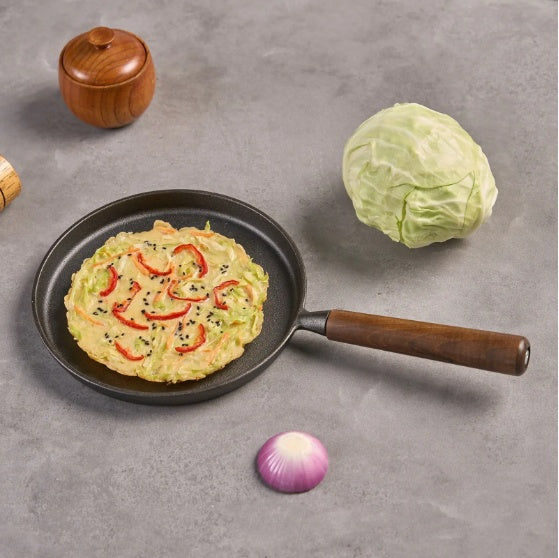 Shopi Vella cast iron pizza pan with wooden handle cooking vegetable pizza on gray surface