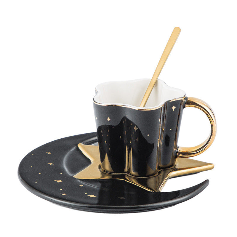 Ceramic cup with star and moon saucer in black and gold with matching gold spoon
