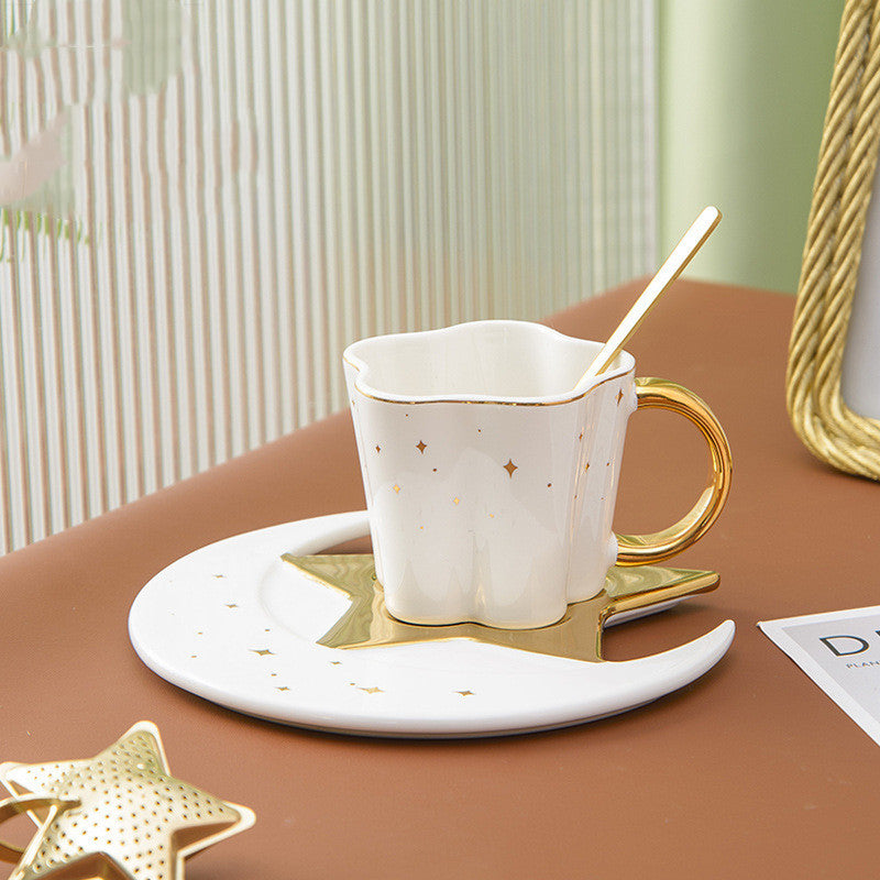 White ceramic cup with star and moon saucer featuring gold accents and a matching spoon
