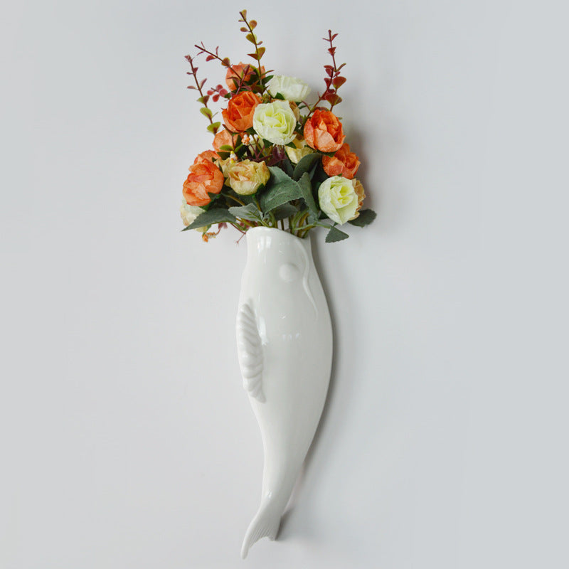 White ceramic goldfish wall vase holding orange and white artificial flowers for home storage decor