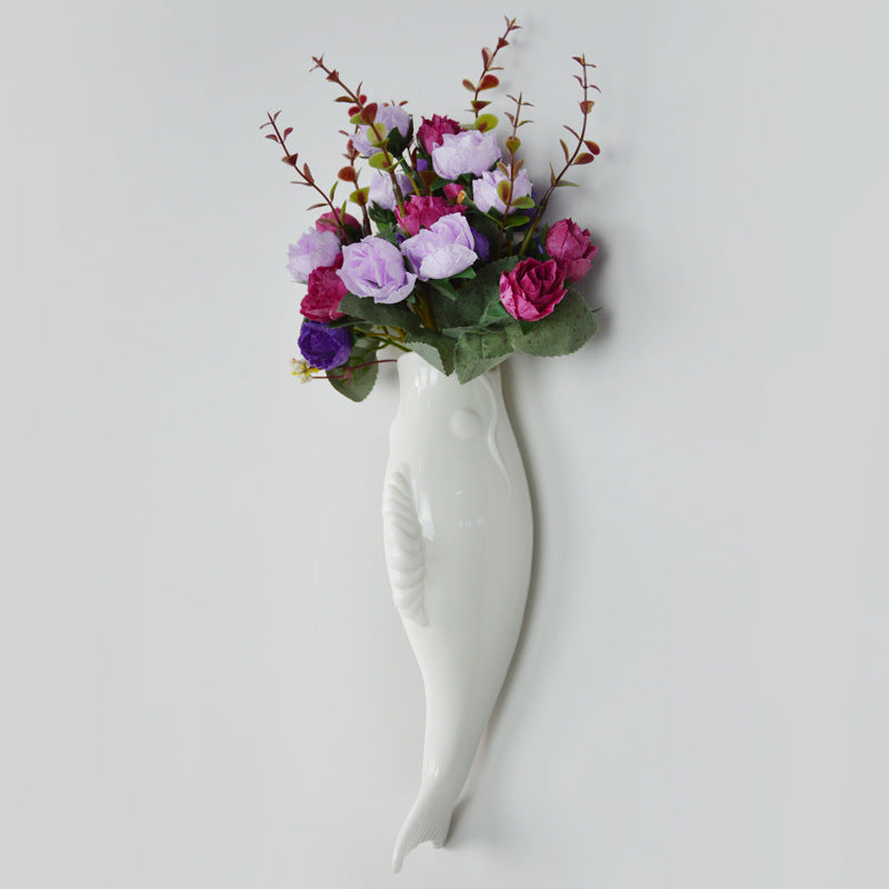 White ceramic goldfish wall vase holding purple and pink artificial flowers for home storage decor