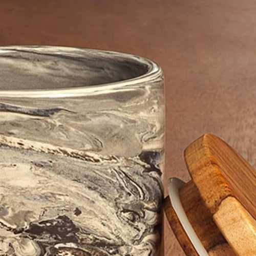 Close-up of a ceramic jar with wooden lid showing marbled texture and natural wood grain detail