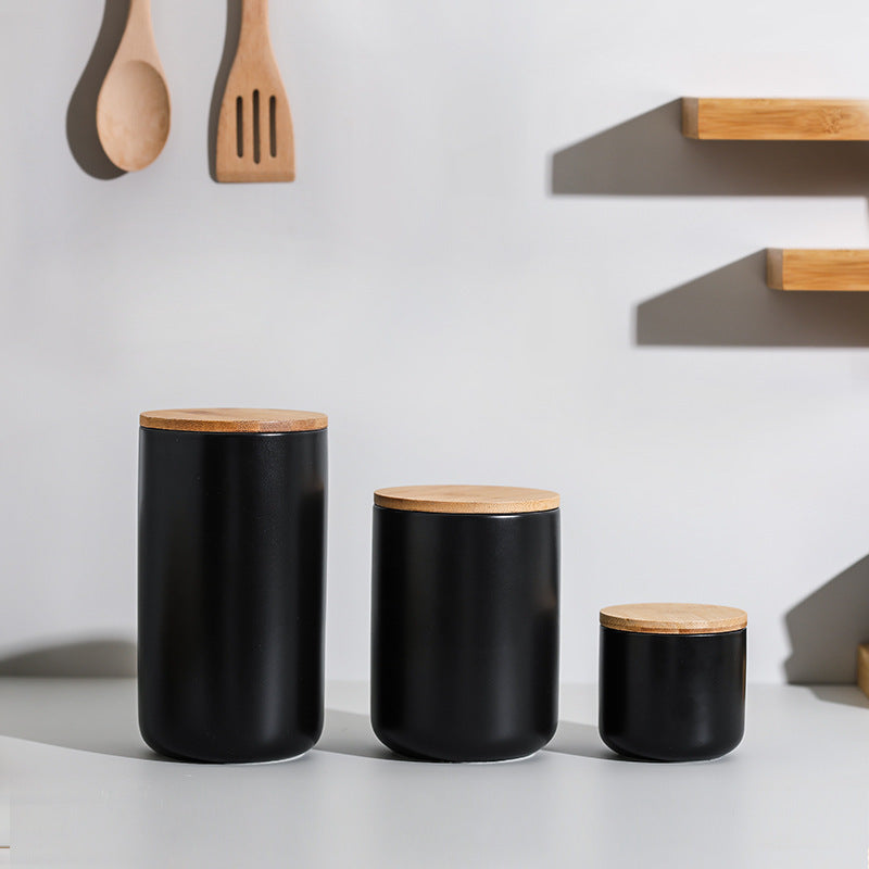 Set of three black ceramic kitchen storage jar containers with wooden lids for pantry organization