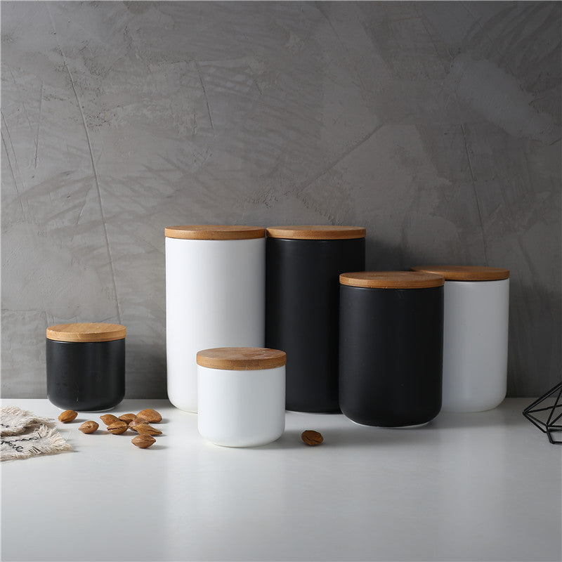 Set of black and white ceramic kitchen storage jar containers with wooden lids for pantry organization