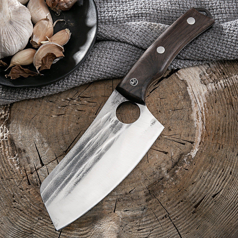 Shopi Vella kitchen deboning knife with wooden handle resting on a rustic wooden surface near garlic cloves