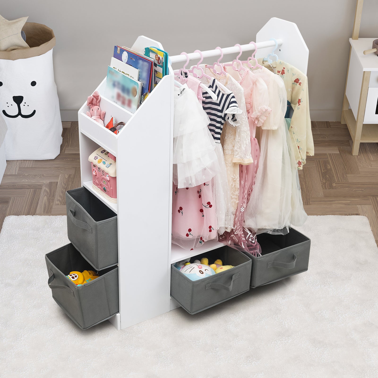 Shopi Vella children's clothing storage rack with hanging dresses and multiple gray fabric bins for toys and books