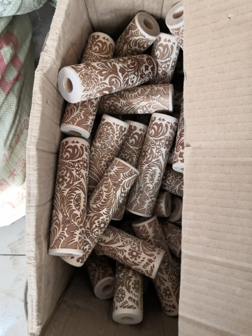 Box of multiple brown Christmas embossing rolling pin handles with intricate floral patterns