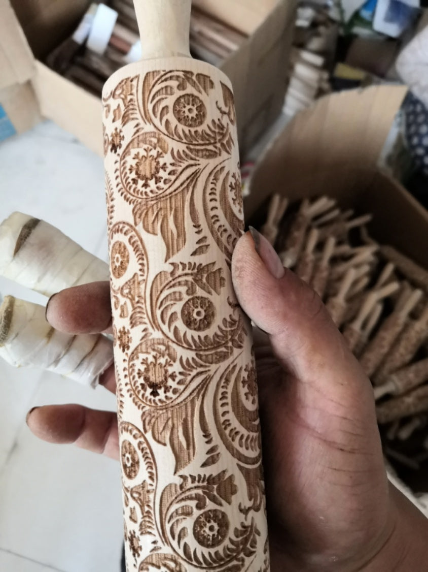 Hand holding Shopi Vella Christmas embossing rolling pin with intricate floral and swirl patterns