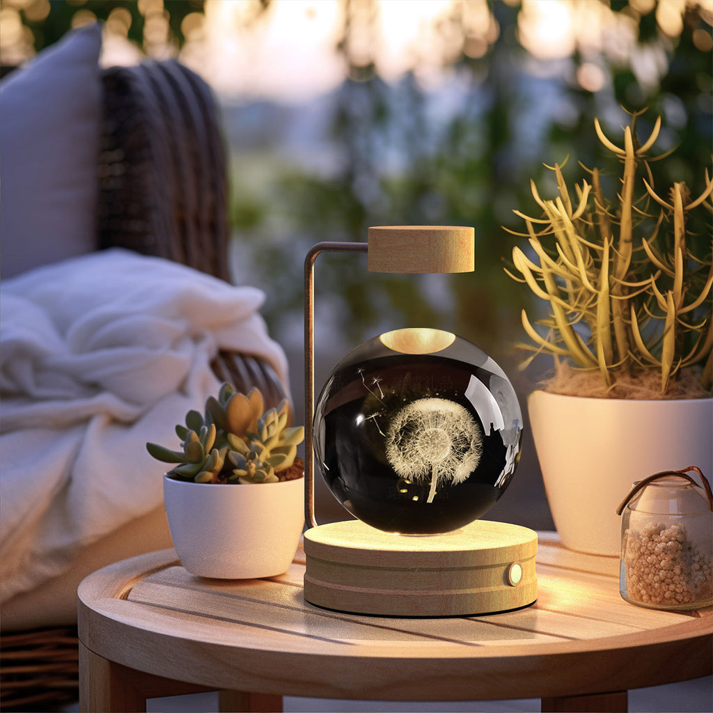 Birthday gift crystal ball lamp with levitating dandelion design on wooden base on outdoor table